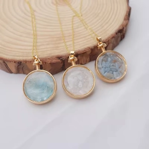 Three circular crystal stone perfume bottle necklaces on a natural wood slice stand