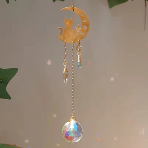 Detail of golden moon and cat suncatcher with crystal prisms reflecting rainbow light spots