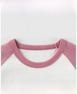 Detail of crew neck and raglan sleeves on a pink and white cotton toddler t-shirt