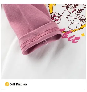 Detail of pink ribbed cuff and cartoon cat print on children's white long sleeve shirt