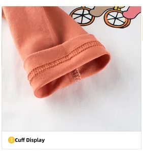 Détail du poignet orange et du tissu en coton blanc avec couture fine sur le t-shirt bébé