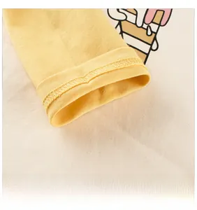 Détail des poignets en coton jaune et des coutures sur un t-shirt enfant à manches longues