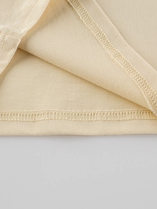 Détail de l'ourlet à double couture sur un T-shirt en tricot crème pour petites filles