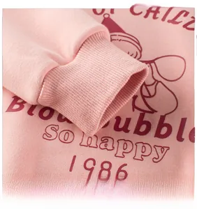 Close-up of pink girls sweatshirt ribbed cuffs and vintage 1986 cartoon print detail