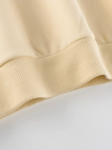 Gros plan de l'ourlet côtelé du sweat-shirt beige à motif pour petites filles en coton