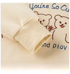 Detail of ribbed cuffs on beige long sleeve sweatshirt with cartoon bear print