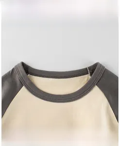 Detail showing the ribbed crew neck and raglan sleeve stitching of the kids cotton tee