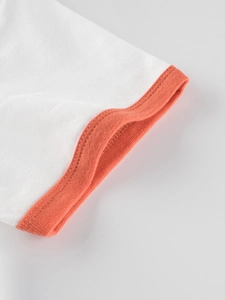 Close-up of white cotton kids T-shirt featuring orange ribbed cuffs and double stitching