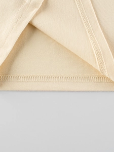 Detailopname van de dubbele naaldzoom op een beige katoenen kinder t-shirt met lange mouwen