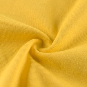 Close-up of ginger yellow knitted cotton fabric showing fine texture and softness