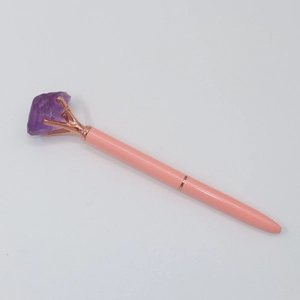 Detailed close-up of pink crystal ballpoint pen with a purple raw stone top in rose gold claw