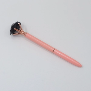 Detail of pink crystal ballpoint pen with raw black stone top in rose gold claw