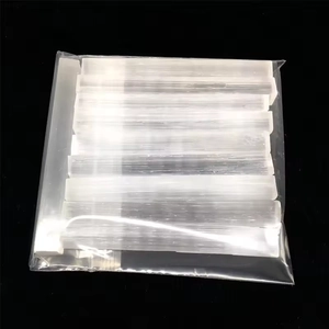 Natural white selenite raw crystal sticks neatly packed in a clear bag on black background