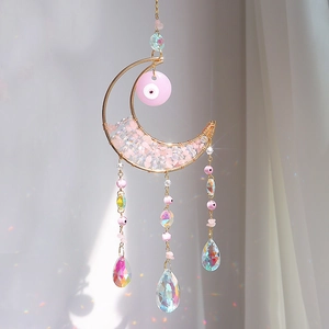 Golden moon suncatcher with pink crystals and evil eye creating rainbow light reflections