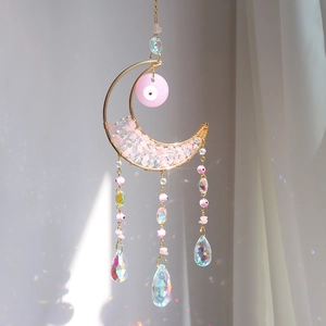 Detail of moon sun catcher with pink crystals creating colorful rainbow reflections