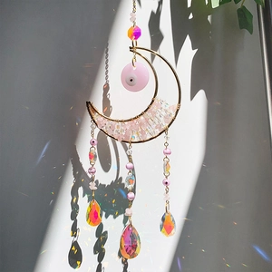 Detail of pink crystal moon suncatcher with evil eye bead and rainbow prism pendants