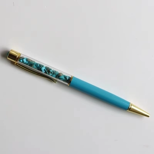 Detail of creative sky blue ballpoint pen filled with turquoise crystals and gold accents
