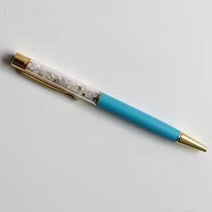 Close-up of sky blue crystal ballpoint pen with gold accents and internal gemstones