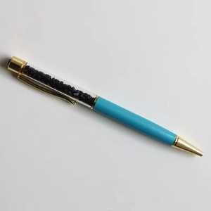 Detailed macro shot of blue crystal ballpoint pen with black decorative gravel stones inside