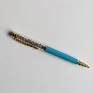 Detail of blue ballpoint pen featuring clear barrel filled with crushed crystals