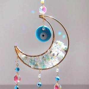 Détail d'attrape-soleil lune avec pierres vertes, œil bleu et prisme en cristal