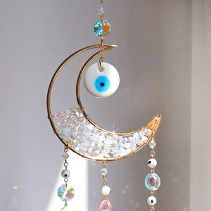 Macro view of crystal moon suncatcher showing rainbow light refraction on a wall