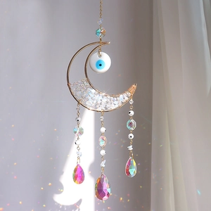Golden moon suncatcher with evil eye and crystal prisms reflecting rainbow light spots