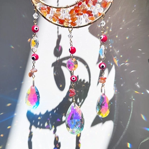 Detail of moon suncatcher with crystals casting rainbow light on a white wall