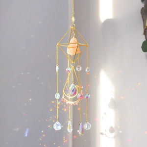 Detail of golden suncatcher with raw pink crystal and rainbow light refraction