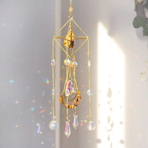 Detail of golden geometric suncatcher with crystal prisms reflecting rainbow light on wall