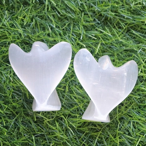 Polished selenite crystal angel carvings set on green grass for home decor display