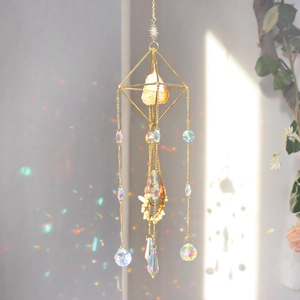 Detail of golden geometric suncatcher casting rainbow light reflections on a white wall