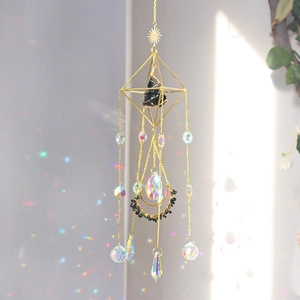 Golden geometric suncatcher with obsidian and prism casting rainbow light on wall