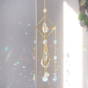 Detail of golden sun catcher reflecting rainbow prism spots on wall in sunlight