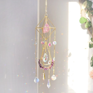 Detail of crystal suncatcher throwing rainbow light on wall with golden metal frames