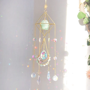 Golden suncatcher showing geometric frame with raw green stone and crystal rainbow prism