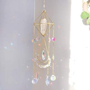 Macro detail of golden geometric frame with natural quartz and rainbow crystal pendants