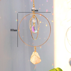 Close-up of golden moon suncatcher featuring rainbow prism and a raw stone pendant