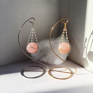 Macro shot of rose quartz sphere hanging on elegant gold and silver S-shaped metal stands