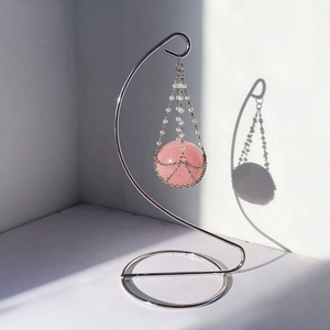 Rose quartz crystal ball hanging on silver metal S-stand with beaded net display