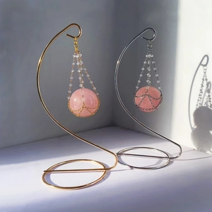Hanging rose quartz sphere set on elegant gold and silver metal stands with shadows