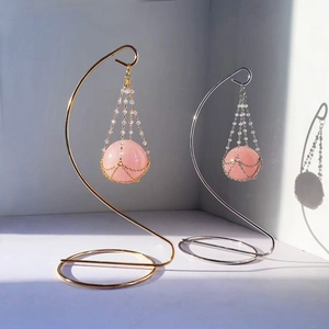 Close-up of rose quartz crystals in gold and silver wire mesh on elegant metal stands