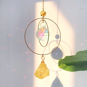 Golden suncatcher with crystal ball and yellow stone creating rainbow light on wall