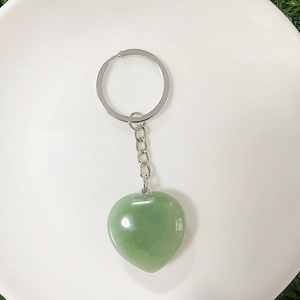 Green aventurine heart crystal keychain with silver ring on a white plate