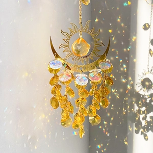 Golden sun and moon crystal suncatcher with rainbow reflections on a white wall