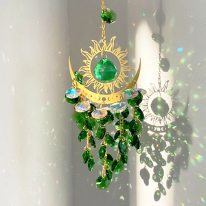 Detailed sun and moon suncatcher with green crystal prisms reflecting rainbows on a wall