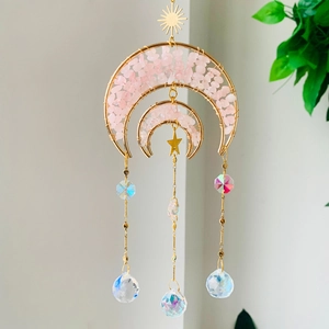 Macro detail of rose quartz moon suncatcher with golden wire and faceted crystal prisms