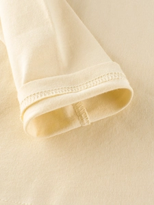 Close-up of cream knit sleeve cuff with double-needle stitching on kids long sleeve t-shirt