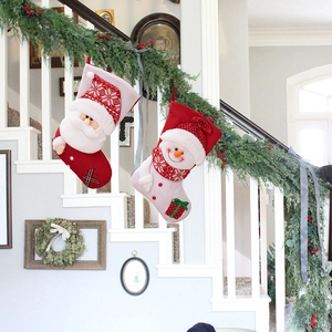 Close-up of knit Christmas stockings with 3D Santa and Snowman characters on stairs