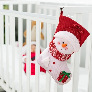 Detail of pink knitted Christmas stocking with 3D snowman doll hanging on a crib